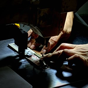 Craftsman sewing leather accessories by hand at Isson Webbing factory
